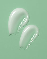 Two droplets of white cream on a light green background