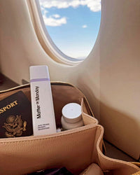 Travel bag with skincare product and passport next to an airplane window