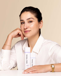 Woman holding a bottle of Matter of Monday products against a beige background