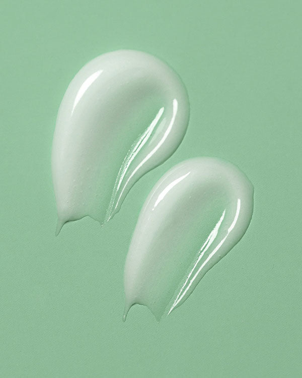 Two smears of white cream on a green background