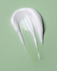 Two smears of white cream on a light green background