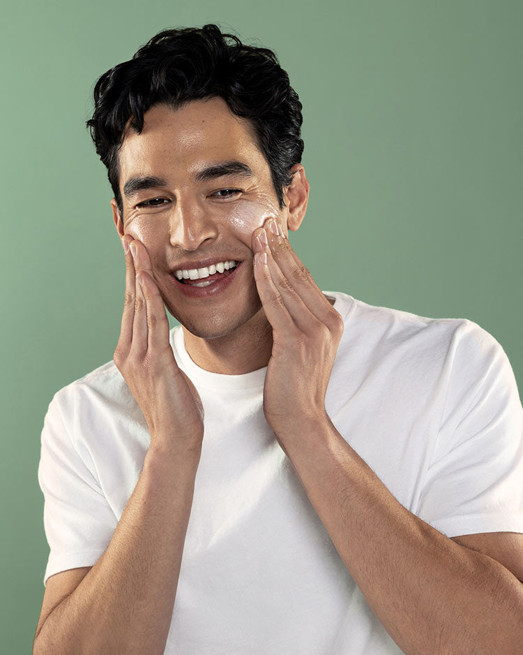 Man applying cream to his face against a green background