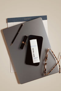 Smartphone with Anti-Blue Light product on a desk with notebook, pen, and glasses.