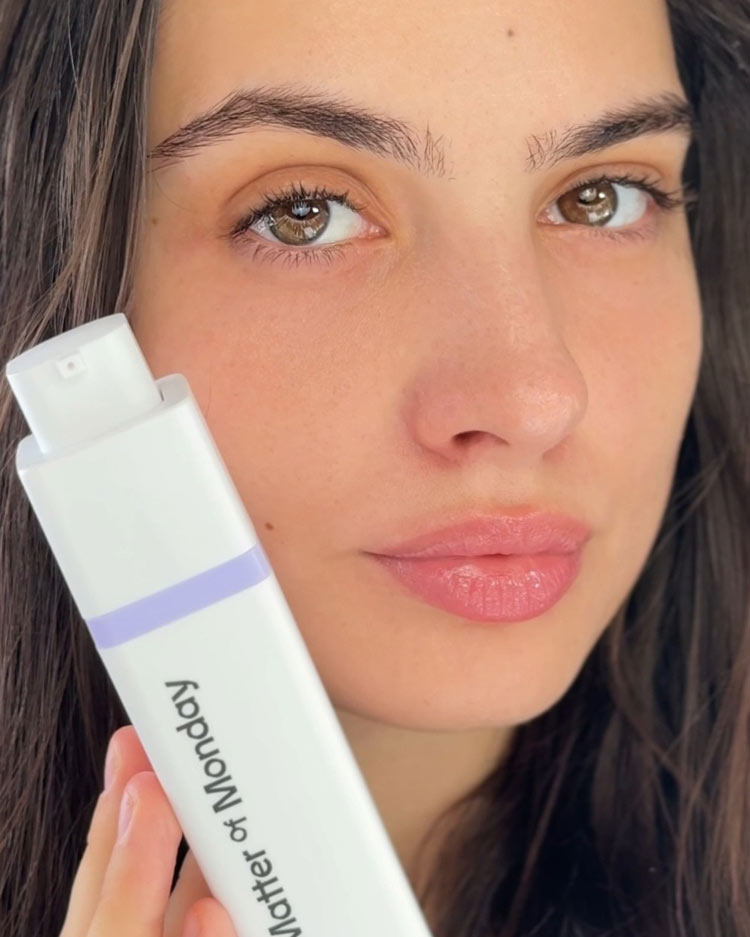 Woman holding a skincare product labeled 'Matter of Monday' close to her face.