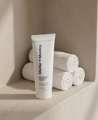 Tube of 'Matter of Monday' product on a shelf with rolled towels in the background