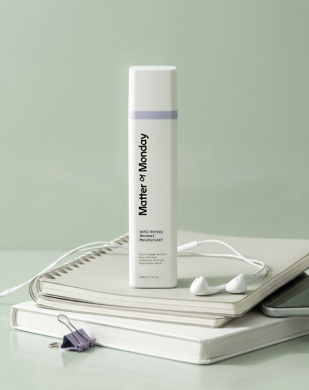 Matter of Monday skincare product on a light gray surface with a notebook and earbuds.