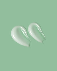 Two dollops of white cream on a light green background
